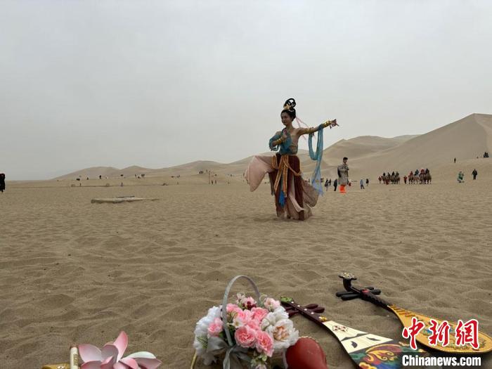 圖為2023年4月底，敦煌大漠“逐舞者”奧楠在鳴沙山月牙泉景區(qū)視頻直播敦煌舞?！●T志軍 攝