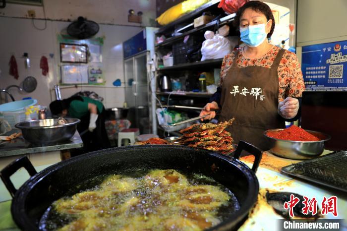 圖為平安驛·河湟民俗文化體驗地內(nèi)的商戶炸干板魚?！⊙Φ?攝