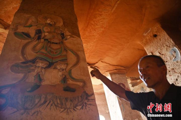 7月15日，甘肅省平?jīng)鍪袥艽h百里石窟長廊羅漢洞石窟內(nèi)，該窟文保員郭建平介紹窟內(nèi)石刻彩繪壁畫。郭建平家中三代人曾自發(fā)保護羅漢洞石窟。羅漢洞石窟遺存40余個窟龕，以北魏至清代風(fēng)格為主。中新社記者 李亞龍 攝</p>
<p>